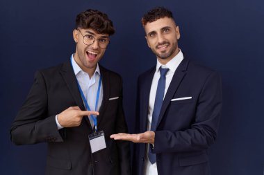 İki İspanyol iş adamı iş kıyafetleri giyip kameraya hayret ediyor ve gülümsüyor.. 