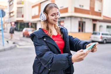 Sokakta video oyunu oynarken kendine güvenen genç sarışın kadın.