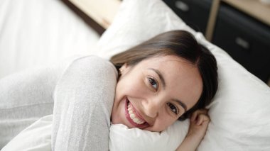 Genç, güzel, İspanyol bir kadın yatakta kendinden emin bir şekilde yatıyor.