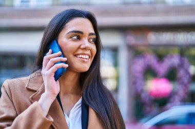 Genç İspanyol kadın gülümsüyor. Kendine güveniyor. Akıllı telefondan konuşuyor.