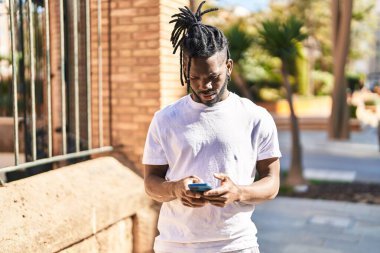 Sokakta akıllı telefon kullanan Afrikalı Amerikalı bir kadın.