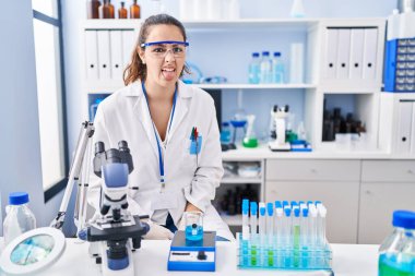 Laboratuvarda çalışan Latin asıllı genç bir kadın komik bir ifadeyle dilini dışarı çıkartıyor. duygu kavramı. 