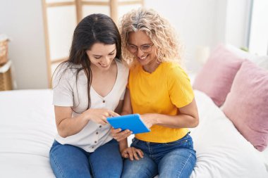 İki kadın anne ve kız yatak odasında dokunmatik ped kullanıyor.