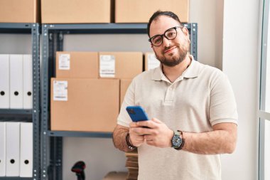 Ofiste akıllı telefon kullanan Latin asıllı genç bir e-ticaret işçisi.