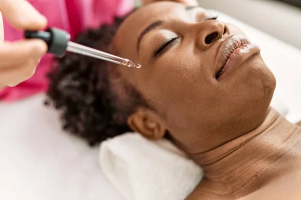 stock image African american woman lying on massage table having facial treatment at beauty salon