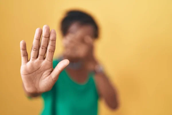 手で目を覆い 悲しいと恐怖の表現でジェスチャーを停止する黄色の背景に立っている恐ろしいアフリカの女性 恥をかかせ否定的な概念 — ストック写真
