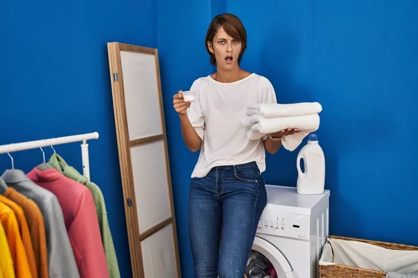 衝撃的な顔できれいな洗濯を保持ブルネットの女性 懐疑的で皮肉を探して オープン口で驚いて — ストック写真