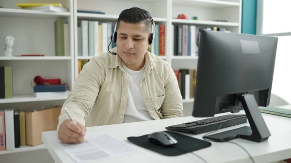 若いヒスパニック系の学生が図書館大学で文書にビデオ通話を書いている — ストック写真
