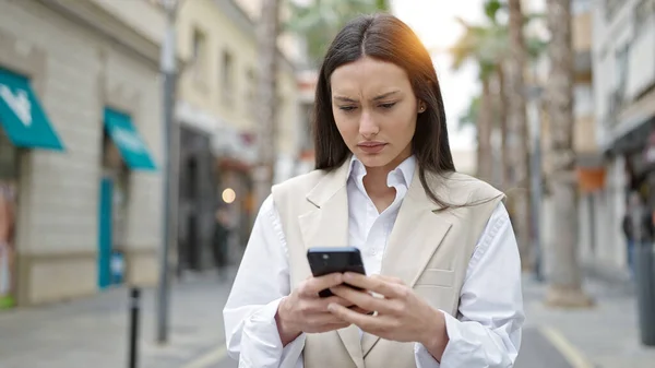 年轻美丽的惊慌失措的女人在街上用带有严肃表情的智能手机 — 图库照片