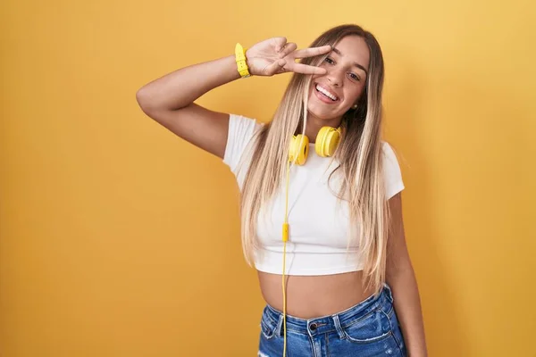 Mujer Rubia Joven Pie Sobre Fondo Amarillo Con Auriculares Haciendo — Foto de Stock