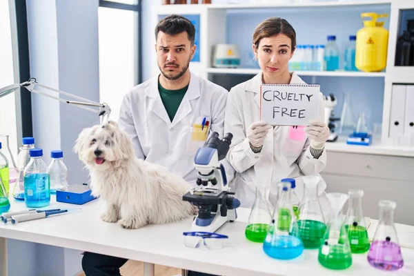 stock image Young hispanic people working at scientist laboratory with dog skeptic and nervous, frowning upset because of problem. negative person. 