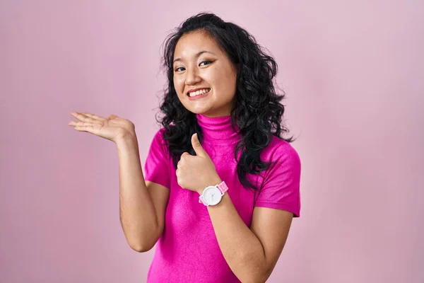 Mladá Asijská Žena Stojící Nad Růžovým Pozadím Ukazující Dlaň Ruku — Stock fotografie