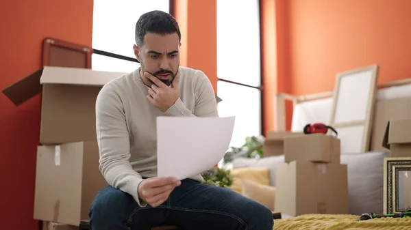 Young Hispanic Man Sitting Sofa Reading Document New Home — Stockfoto