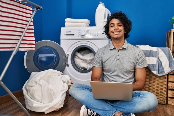 在洗衣房用笔记本电脑等洗衣机的年轻人 — 图库照片