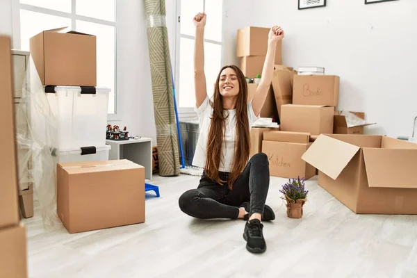 stock image Young hispanic woman smiling confident sitting on floor with hands raised up at new home