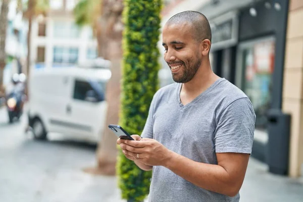 年轻的拉丁男人在街上用智能手机充满自信地微笑 — 图库照片