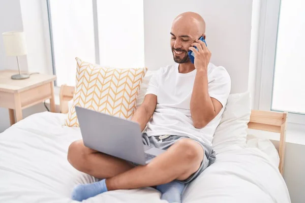 Young Bald Man Using Laptop Talking Smartphone Bedroom — 图库照片