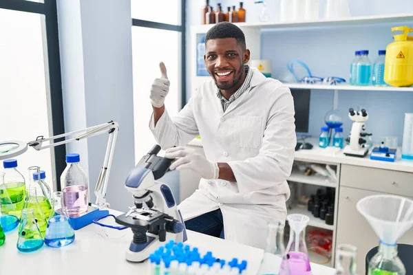 科学研究所で働くアフリカ系アメリカ人男性は笑顔でポジティブで 親指を立てて優れた承認サインをする — ストック写真