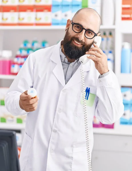 Young Bald Man Pharmacist Talking Telephone Holding Pills Bottle Pharmacy — Stock Photo, Image