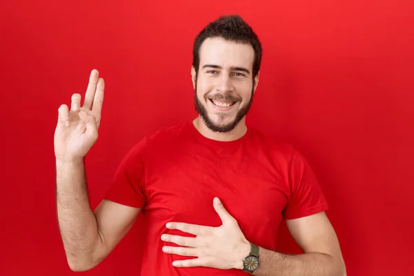 Νεαρός Ισπανός Φοράει Κόκκινο Μπλουζάκι Χαμογελώντας Βρίζοντας Χέρι Στο Στήθος — Φωτογραφία Αρχείου