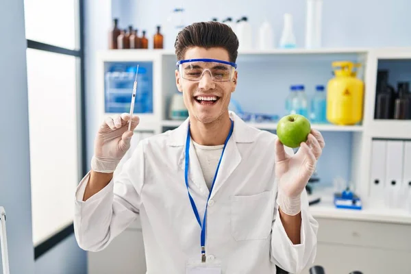 Mladý Hispánec Pracující Laboratoři Vědec Drží Jablko Úsměvem Hlasitě Směje — Stock fotografie