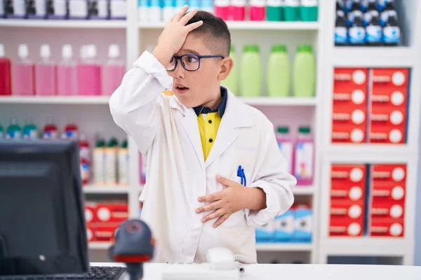 Jovem Criança Hispânica Trabalhando Farmácia Farmácia Surpreendida Com Mão Cabeça — Fotografia de Stock