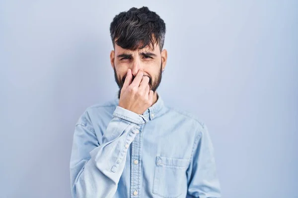 Young Hispanic Man Beard Standing Blue Background Smelling Something Stinky — Stock Photo, Image