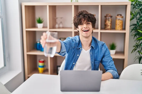 Jonge Spaanse Man Die Thuis Laptop Drinkwater Gebruikt — Stockfoto