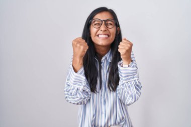 Gözlüklü genç İspanyol kadın başarı için heyecanlanıyor kolları havada ve gözleri kapalı zaferi kutluyor gülümsüyor. Kazanan konsept. 