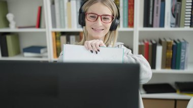 Kütüphane üniversitesinde not defterini gösteren sarışın genç bir kadın.