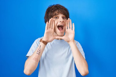 Mavi arka planda dikilmiş, gülümseyen, gülümseyen, elleri havada bir böceği dikizleyen İspanyol genç adam. Şaşırdım ve çıktım. 