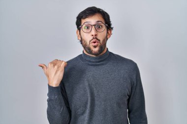 İzole edilmiş arka planda duran yakışıklı latin adam elleri yana dönük, ağzı açık şaşkın bir ifadeyle şaşırdı.. 