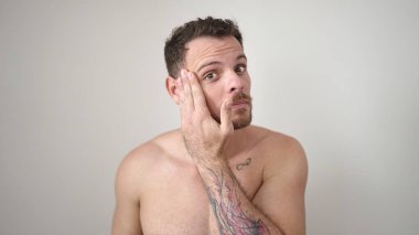 Beyaz arka plan üzerinde ciddi bir ifadeyle duran beyaz tenli genç adam.