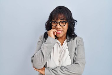 Hispanic woman standing over isolated background looking stressed and nervous with hands on mouth biting nails. anxiety problem. 