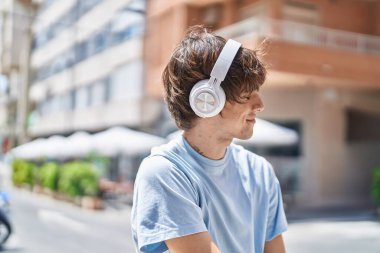 Young blond man listening to music at street