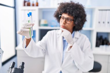 Laboratuvarda test tüpleri tutan Afrikalı Amerikalı kadın bilim adamı.