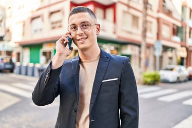 Young hispanic man executive smiling confident talking on smartphone at street