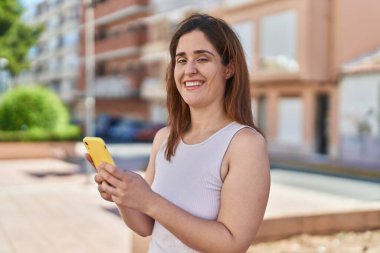 Sokakta akıllı telefon kullanan kendine güvenen genç bir kadın.