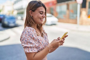 Sokakta akıllı telefon kullanan kendine güvenen genç bir kadın.