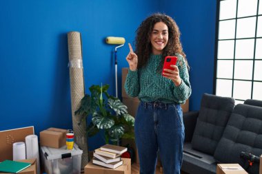 Yeni evinde akıllı telefon kullanan genç İspanyol kadın bir fikre ya da soru işaretine şaşırdı ve mutlu bir yüzle işaret etti. 