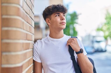 Sokak ortasında rahat bir ifadeyle sırt çantası takan genç İspanyol bir öğrenci.