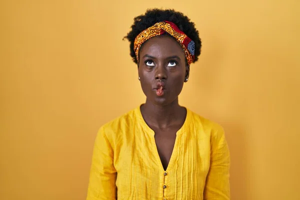 アフリカのターバンを身に着けているアフリカの若い女性は 狂気とコミカルなジェスチャーで魚の顔を作る 面白い表現 — ストック写真
