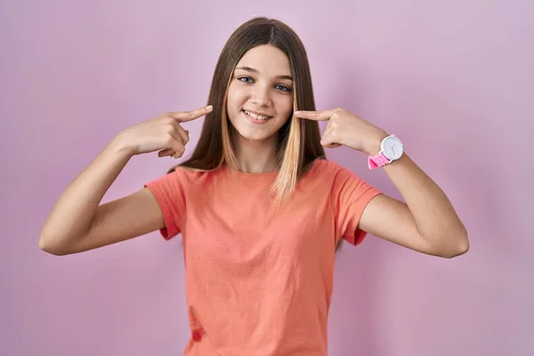 站在粉色背景上的少女笑容满面 用手指 牙齿和嘴指指点点 牙齿健康概念 — 图库照片