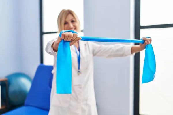 Middle Age Blonde Woman Wearing Physiotherapist Uniform Using Elastic Band — Stockfoto
