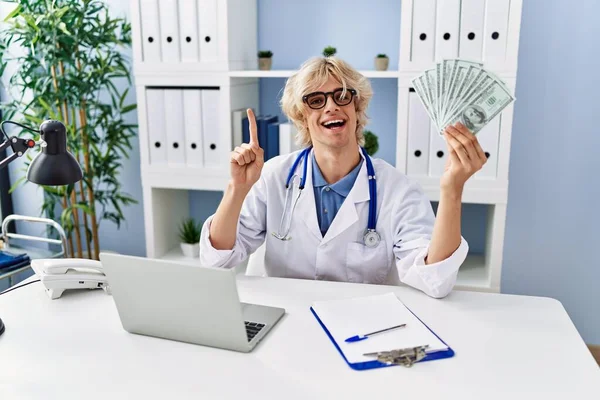 Jovem Médico Segurando Dinheiro Sorrindo Com Uma Ideia Pergunta Apontando — Fotografia de Stock