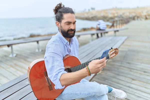 Νεαρός Ισπανός Μουσικός Κρατώντας Κλασική Κιθάρα Χρησιμοποιώντας Smartphone Στην Παραλία — Φωτογραφία Αρχείου