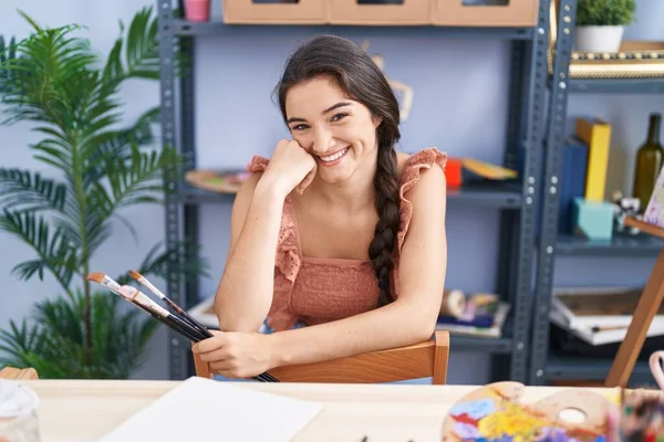 Młoda Latynoska Artystka Uśmiecha Się Pewnie Trzymając Pędzle Pracowni Artystycznej — Zdjęcie stockowe