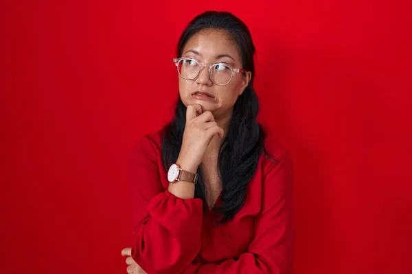 Asyalı Genç Bir Kadın Kırmızı Arka Planda Duruyor Bir Soru — Stok fotoğraf