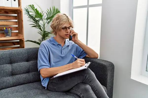Young Blond Man Psychologist Writing Document Talking Smartphone Psychology Clinic — ストック写真