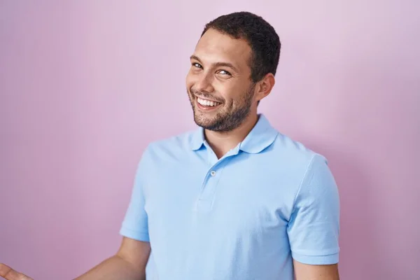 西班牙裔男子站在粉红的背景上 笑容满面 张开双臂表示友好的欢迎 积极而自信的问候 — 图库照片